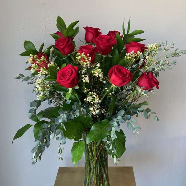 Tall bouquet of red roses in a clear glass vase