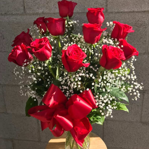 Bouquet of red roses with baby's breath in a glass vase and red ribbon