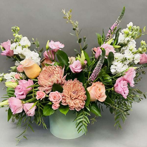 Pink and peach floral arrangement in a pale green vase