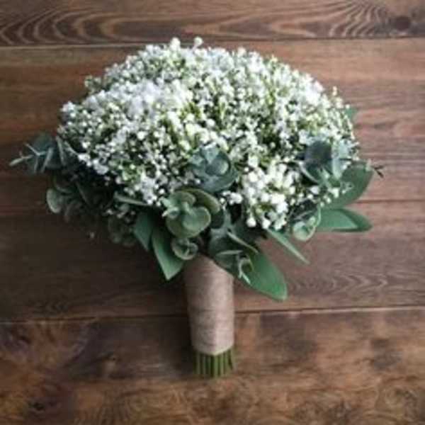 Round bouquet of tiny white flowers with green foliage and a wrapped handle