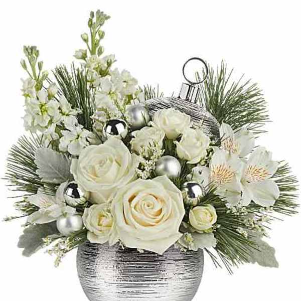 White roses and blossoms in a silver vase with pine accents and ornaments