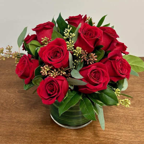 Red roses arranged in a green glass vase