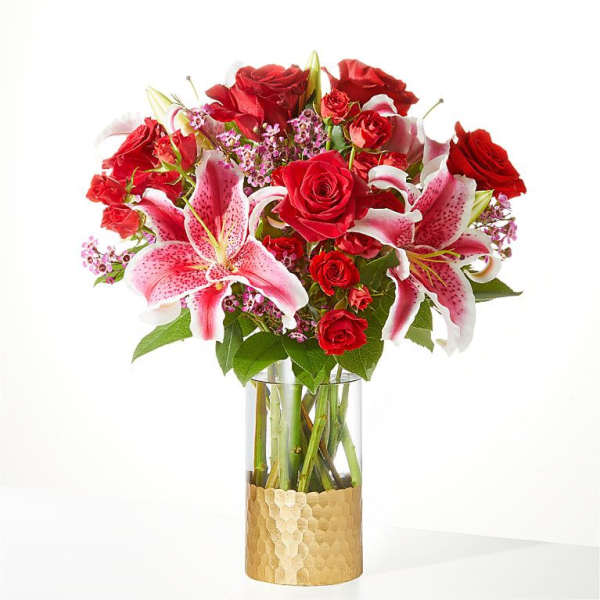 Bouquet of red roses and pink lilies in a clear glass vase