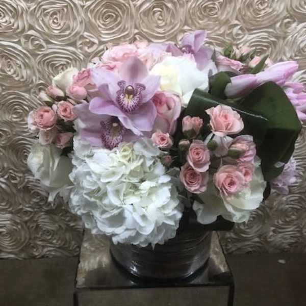Pink and white floral arrangement in a black vase