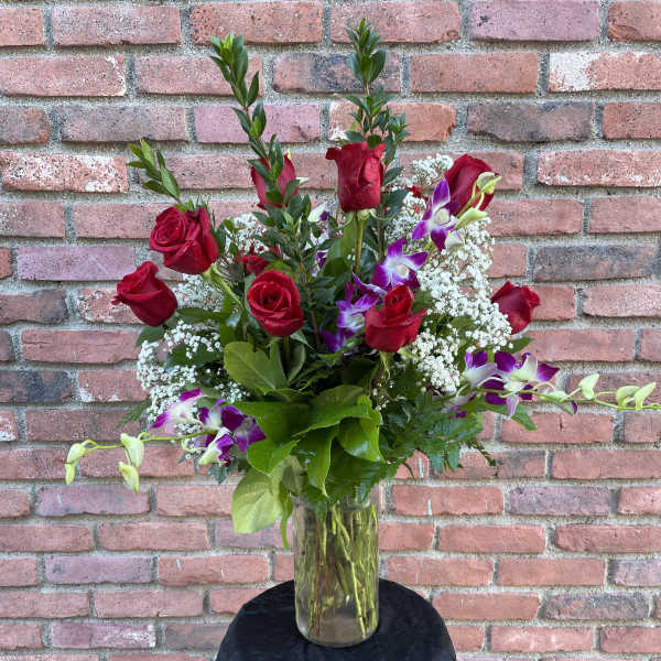 Red roses and purple orchids in a glass vase