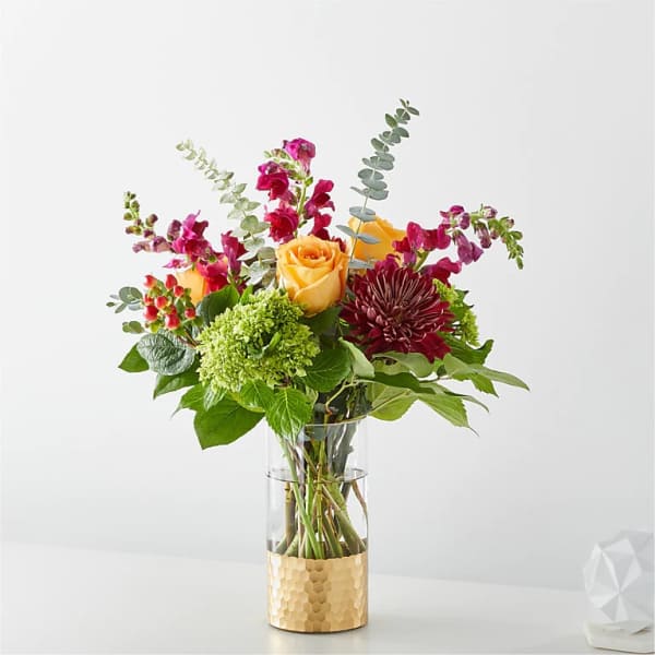 Mixed bouquet in a clear glass vase with yellow roses and magenta blooms