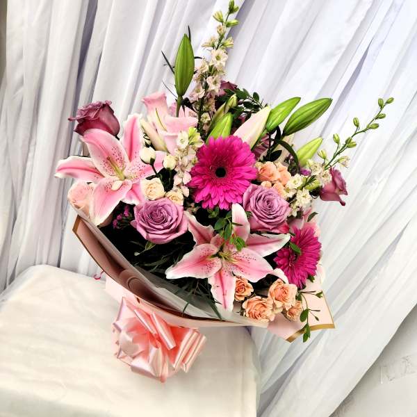 Bouquet of pink lilies, purple roses, and magenta gerbera daisies