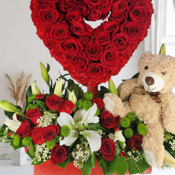 Heart-shaped red rose arrangement with a teddy bear and mixed flowers