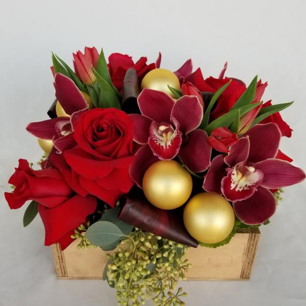 Red roses and burgundy orchids arranged in a box with gold ornaments