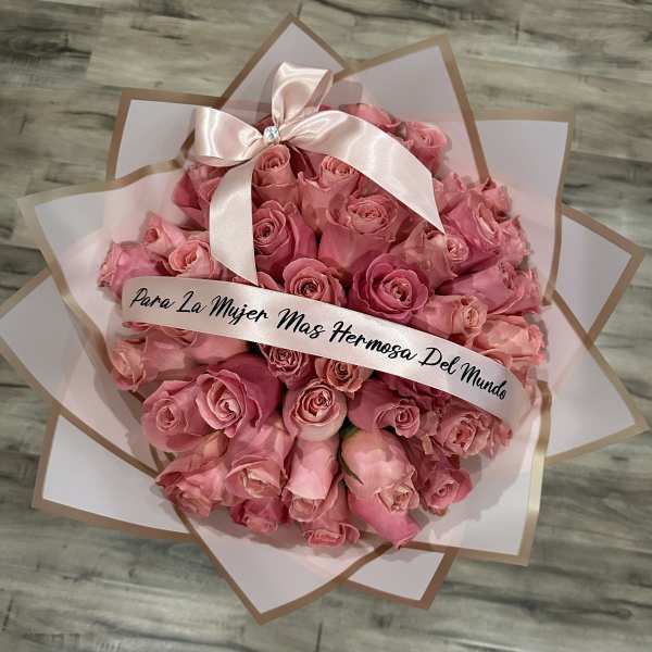 Pink rose bouquet wrapped in white and tan paper with a satin bow