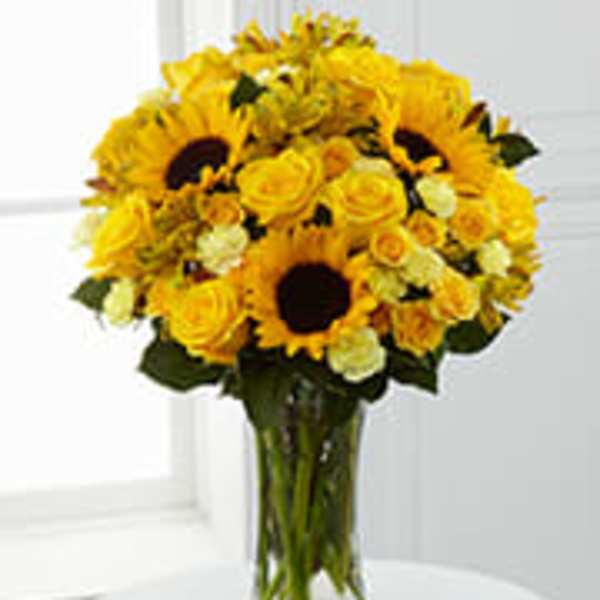 Yellow sunflowers and roses in a clear glass vase