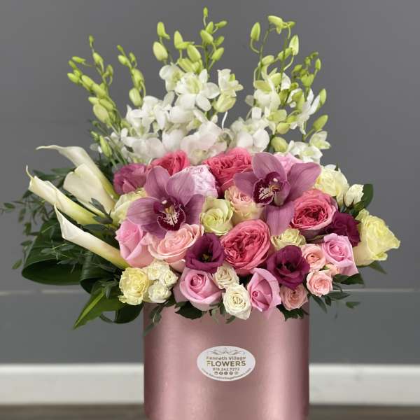Pink and white mixed flower arrangement in a round pink box