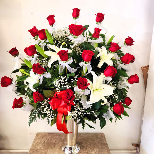 Large arrangement of red roses and white lilies in a tall vase
