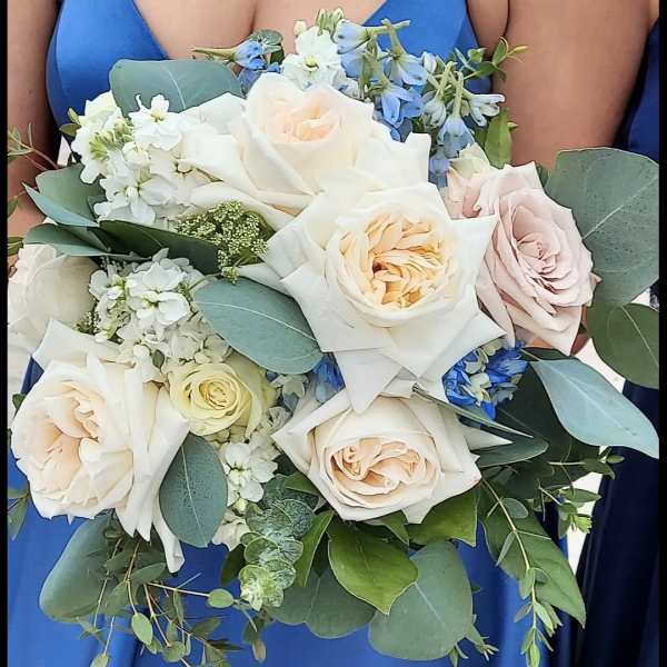 Woman holding a bouquet of pale roses and blue flowers