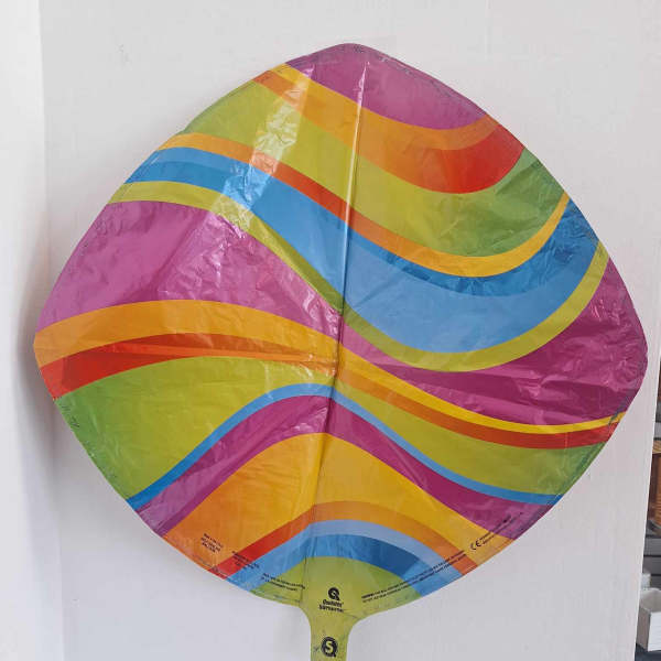 Rainbow-striped foil balloon against a white wall