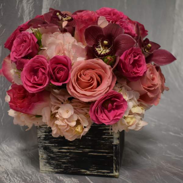 Pink and peach roses with orchids in a black square container