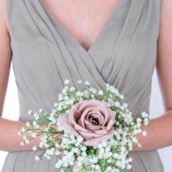 Bridesmaid holding a pink rose wrist corsage with baby's breath and ribbon