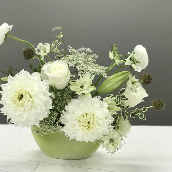 White flowers arranged in a light green bowl vase