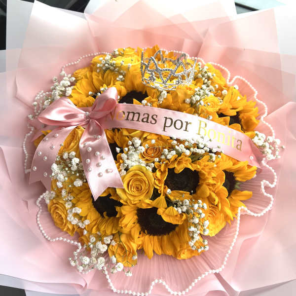 Bouquet of yellow sunflowers and roses with a pink ribbon and tiara