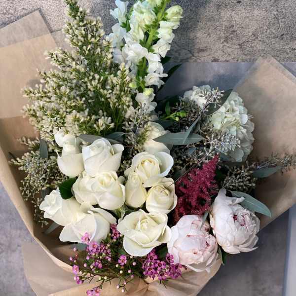 Bouquet of white roses, peonies, and snapdragons with pink accents