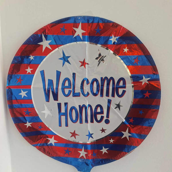Round foil balloon with "Welcome Home!" text in red, white, and blue