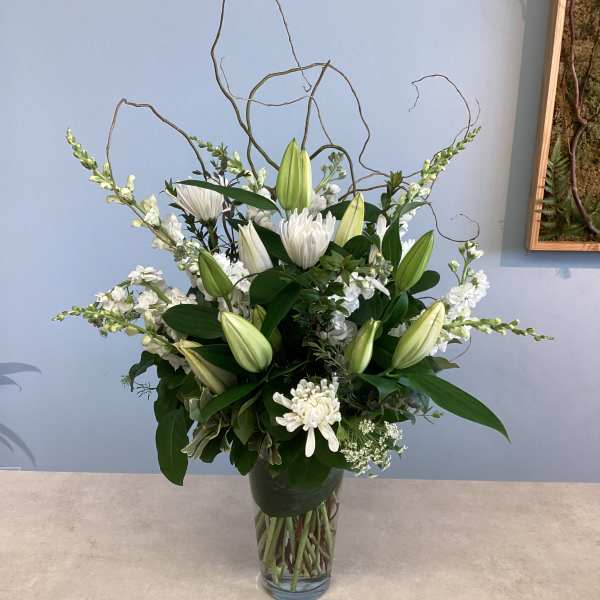 White lilies and chrysanthemums arranged in a clear glass vase