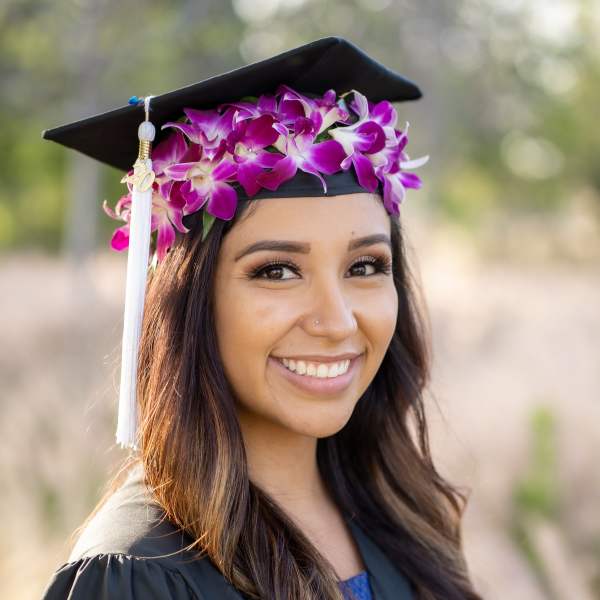 Graduate wearing a cap with purple orchid flowers and a tassel