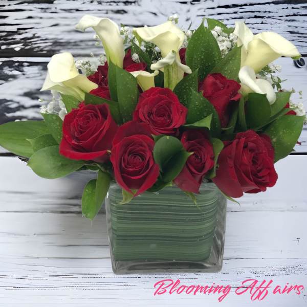 Red roses and white calla lilies in a square glass vase
