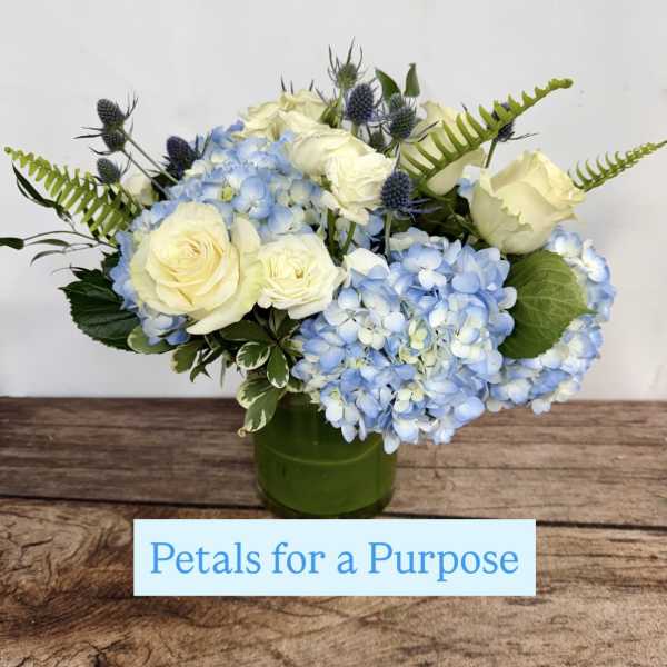Blue hydrangeas and white roses arranged in a green vase