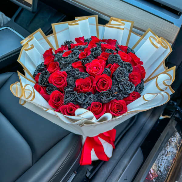 Bouquet of red roses wrapped in white paper with gold trim
