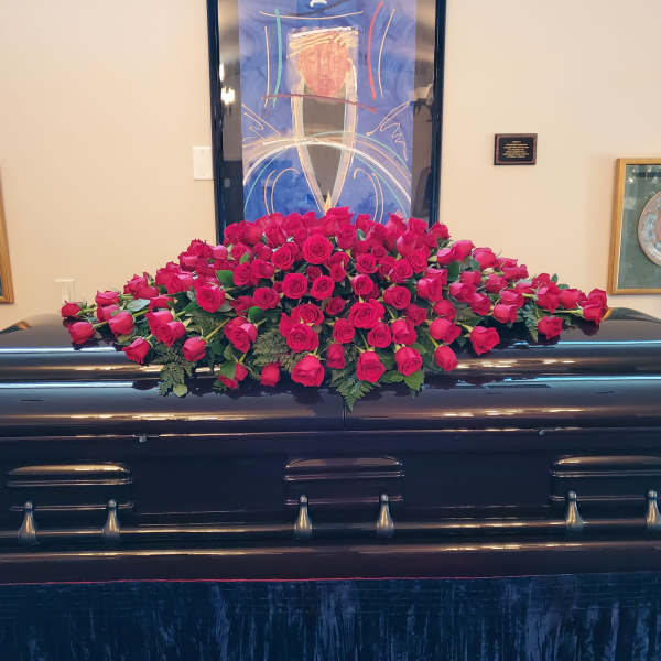 Pink rose casket spray on a dark casket