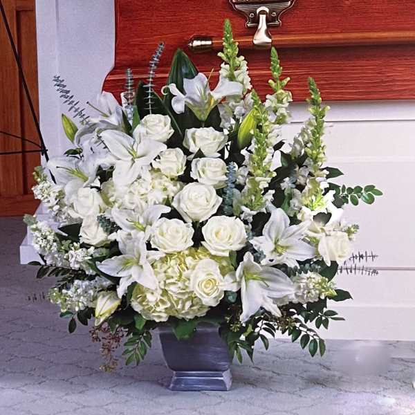 White lilies and roses arranged in a silver vase