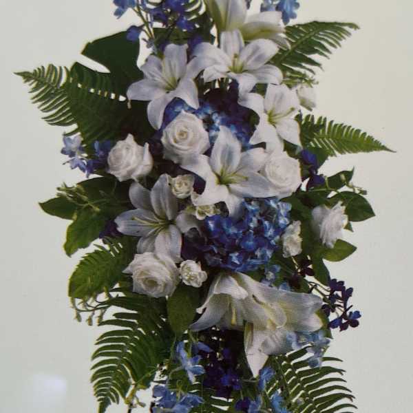 White lilies and blue flowers arranged on a standing easel