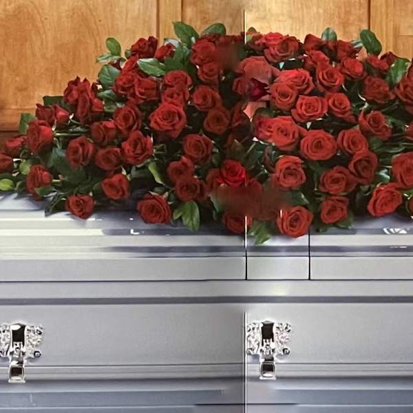 Red rose casket spray on a silver casket