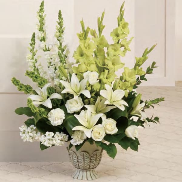 White lilies and roses arranged in a decorative vase with tall green spikes