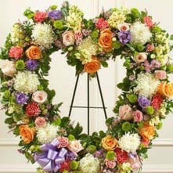 Large floral wreath on a black easel with a purple ribbon