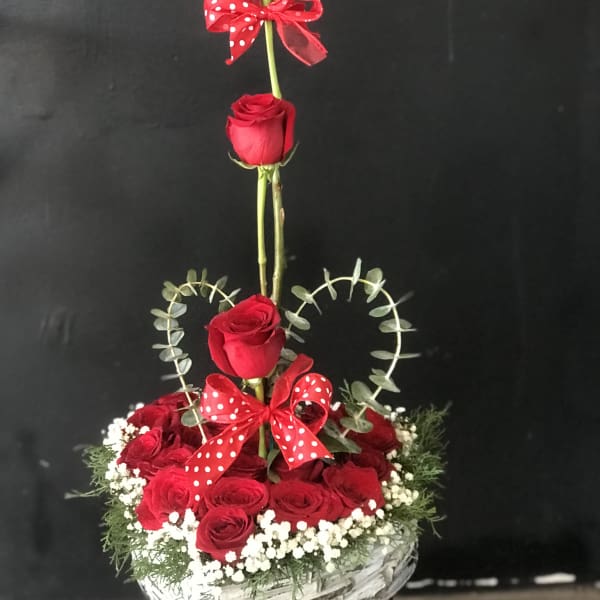 Heart-shaped rose arrangement in a white basket with red bows
