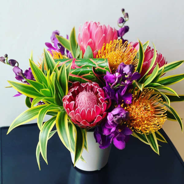 Bright tropical bouquet in a white pot with pink and purple blooms