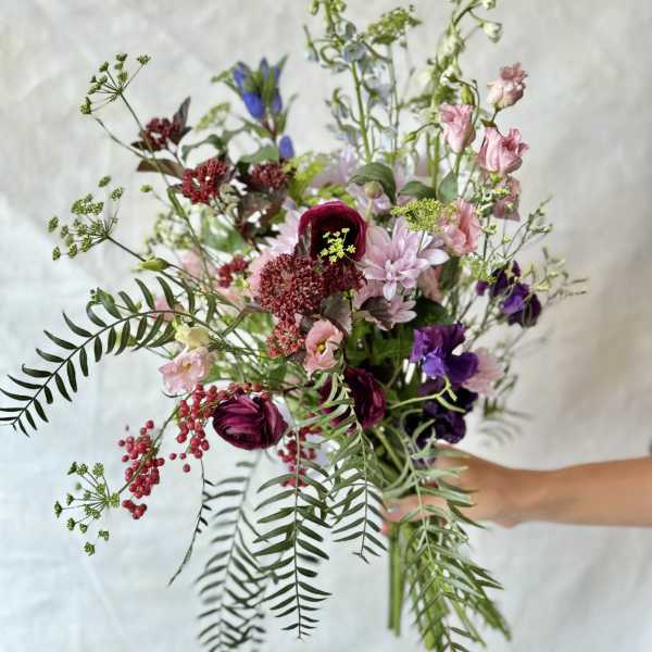 Loose bouquet of mixed pink, purple, and white flowers with airy greenery