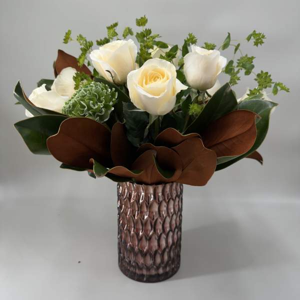 White roses and green blooms in a textured glass vase