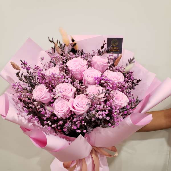 Pink rose bouquet wrapped in pastel pink paper with a ribbon