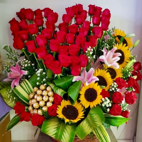Large bouquet of red roses, sunflowers, and pink lilies in a basket