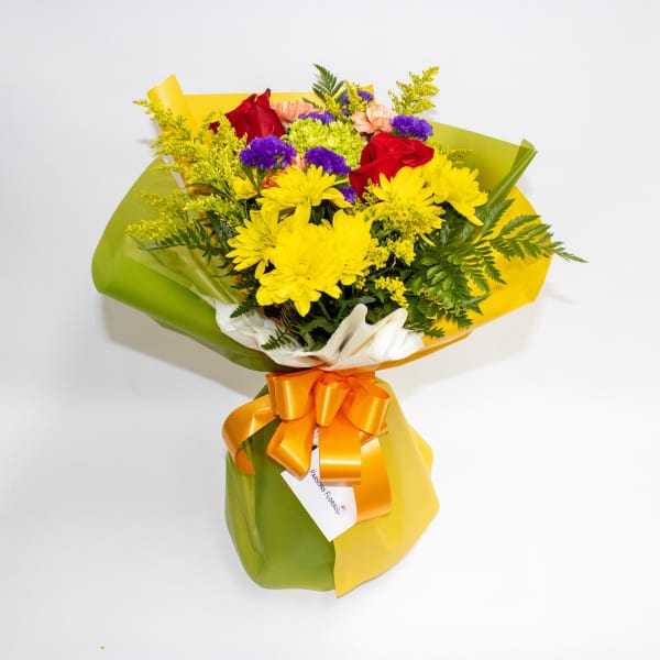 Bouquet of yellow daisies and red roses wrapped in green and yellow paper