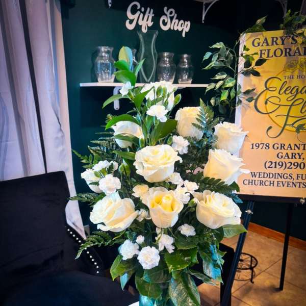 White roses and carnations in a teal glass vase