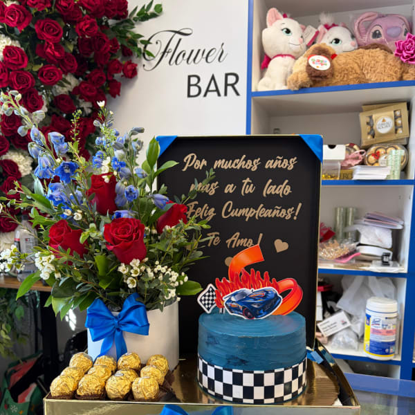 Red rose arrangement with blue flowers, chocolates, and a blue cake in a gift box