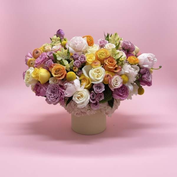 Mixed bouquet of pastel roses and ranunculus in a round vase