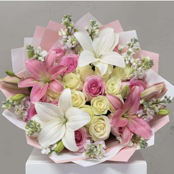Pink and white bouquet with lilies and roses wrapped in pastel paper