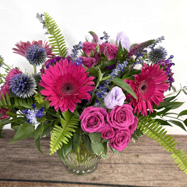 Bouquet of hot pink flowers and purple blooms in a clear glass vase