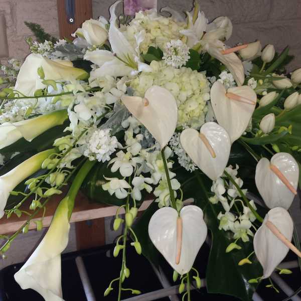 White floral casket spray with calla lilies, orchids, and anthuriums
