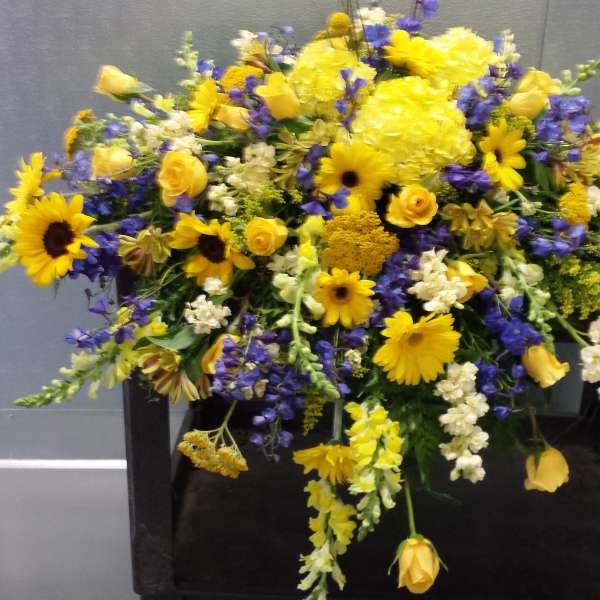 Large yellow and blue floral arrangement on a dark stand